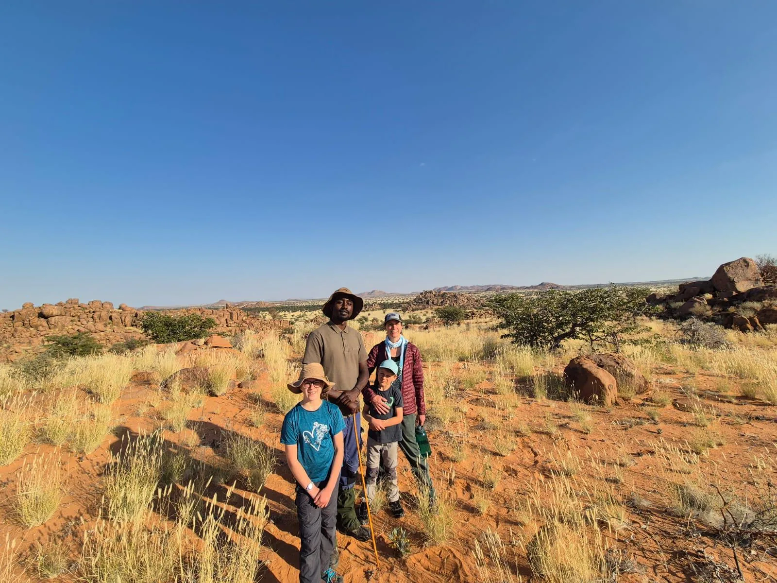 Guests pausing with their guide among Damaraland granite and grassland.
