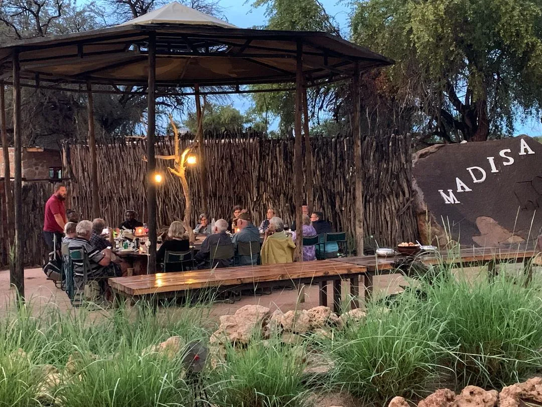 Guests sharing an evening meal in the outdoor dining area at Madisa Camp.