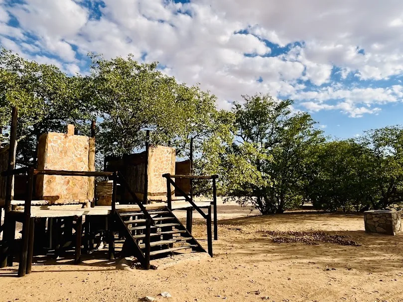 An elevated private campsite bathroom beneath Mopane trees at Madisa Camp.